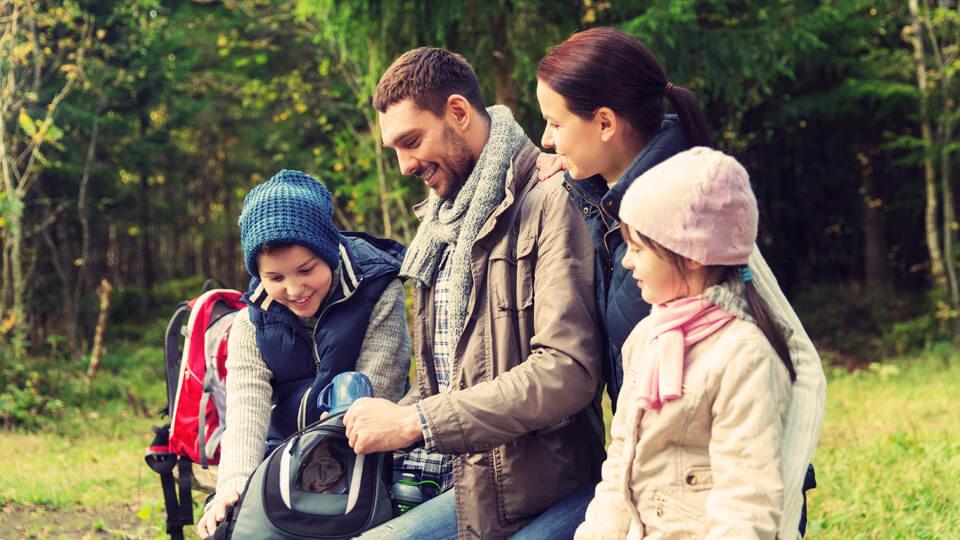 A young family smiling outside in the forest on a camping holiday